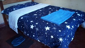 Een bed met een sprei met sterafbeelding en een blauwe handdoek.