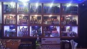 Een bar met flessenkasten en een toonbank met glazen en een menukaart.