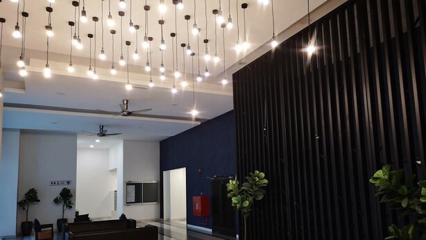 A modern lobby with a ceiling fan, hanging lights, a reception desk, and potted plants. - YOYO Homestay (Johor Bahru)