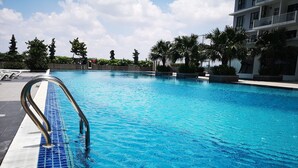 A swimming pool with a metal ladder, surrounded by palm trees and a building. - YOYO Homestay (Johor Bahru)