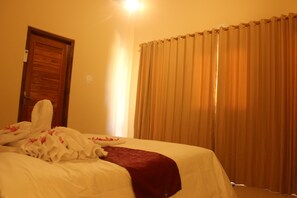 A hotel room with a neatly made bed, a wooden door, and a curtain. - Agasta Villa (Penida Island)