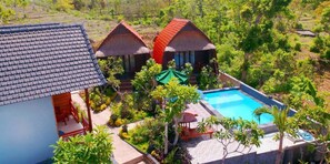 A resort with two thatched-roof cabins, a swimming pool, and lush greenery. - Agasta Villa (Penida Island)