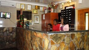 A reception area with a stone counter, framed certificates on the wall, and a Christmas tree. - Mashamba Country House (Giyani)