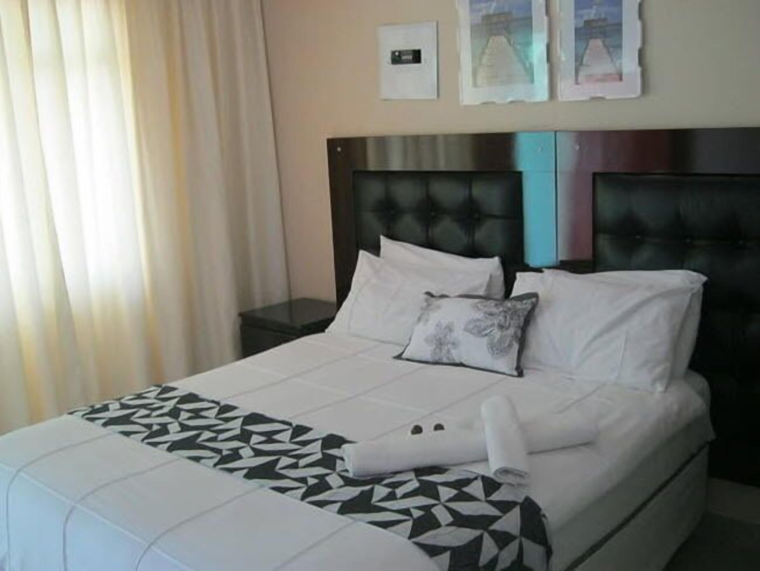 A hotel room with a bed, a nightstand, a pillow, and a blanket.
