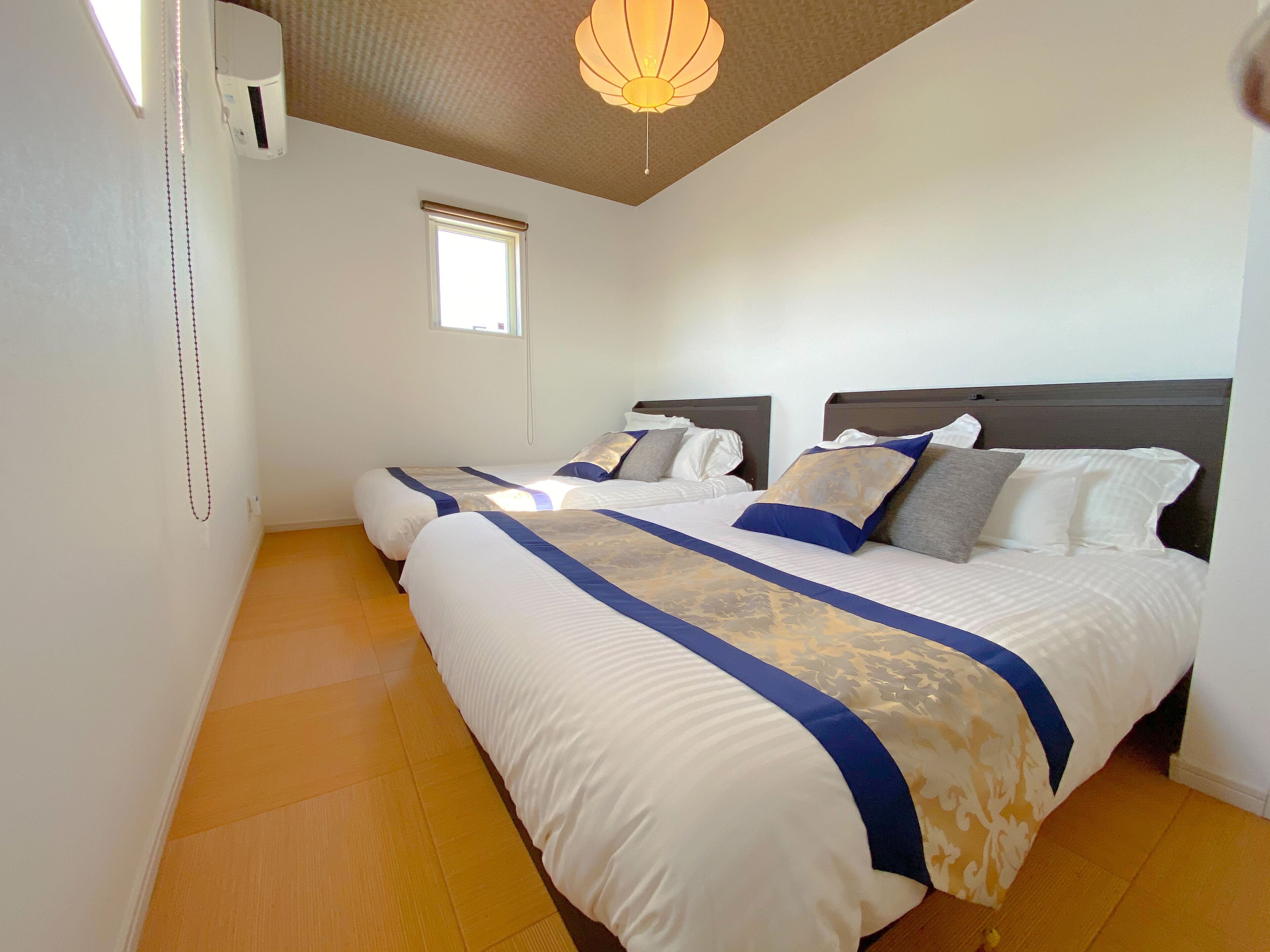 Habitación de hotel con dos camas, ventana y ventilador de techo.