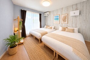 A hotel room with two beds, a large window with curtains, a wall-mounted air conditioner, and framed pictures. - Grandioso Okinawa Pool Villa Onna 4 (Onna)