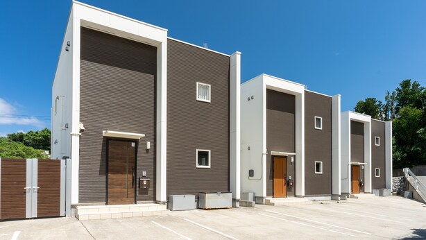 A row of modern, single-story buildings with large doors and small windows, likely a hotel or apartment complex. - Grandioso Okinawa Pool Villa Onna 4 (Onna)