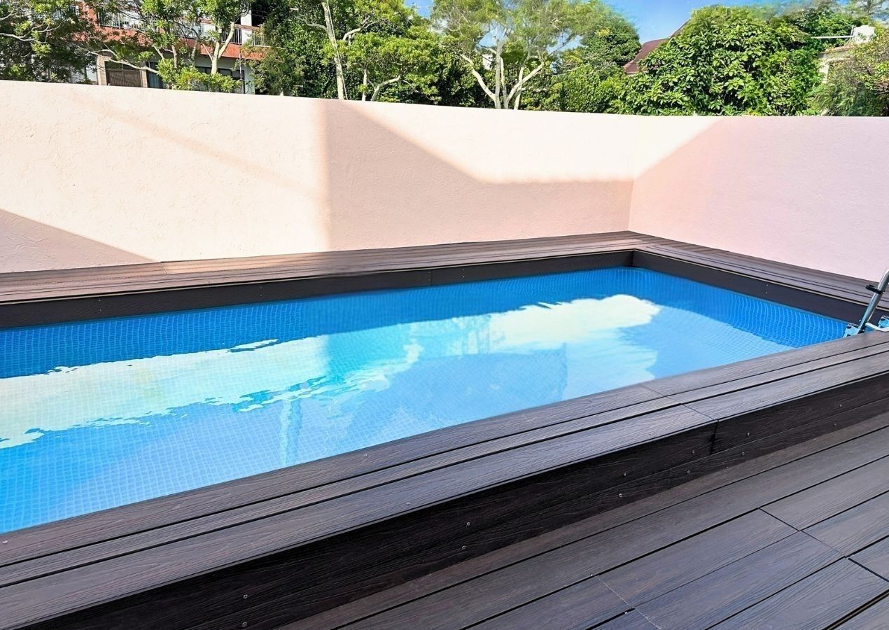 Ein rechteckiger Swimmingpool mit einer umlaufenden Holzterrasse.