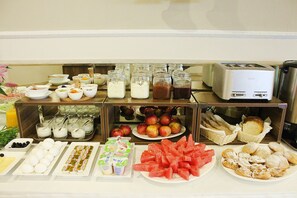 Een buffet met diverse gerechten, waaronder fruit, gebak en drankjes.