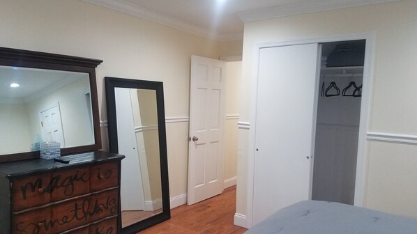 A bedroom with a dresser, a mirror, a door, and a closet.