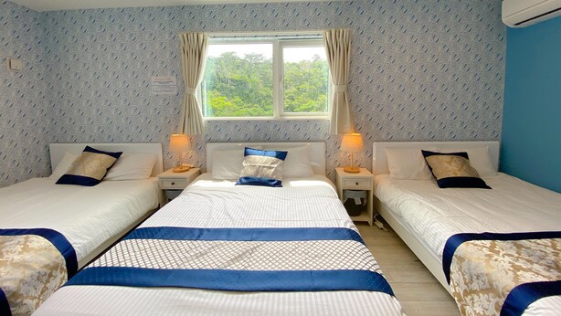 A hotel room with two beds, a window with curtains, patterned wallpaper, and a ceiling light. - Grandioso Okinawa Pool Villa Onna 6 (Onna)