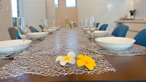 A dining table set with white plates, clear glasses, and blue chairs. - Grandioso Okinawa Pool Villa Onna 6 (Onna)