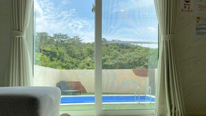 A room with a view of a swimming pool, a chair, and a flower on the bed. - Grandioso Okinawa Pool Villa Onna 6 (Onna)
