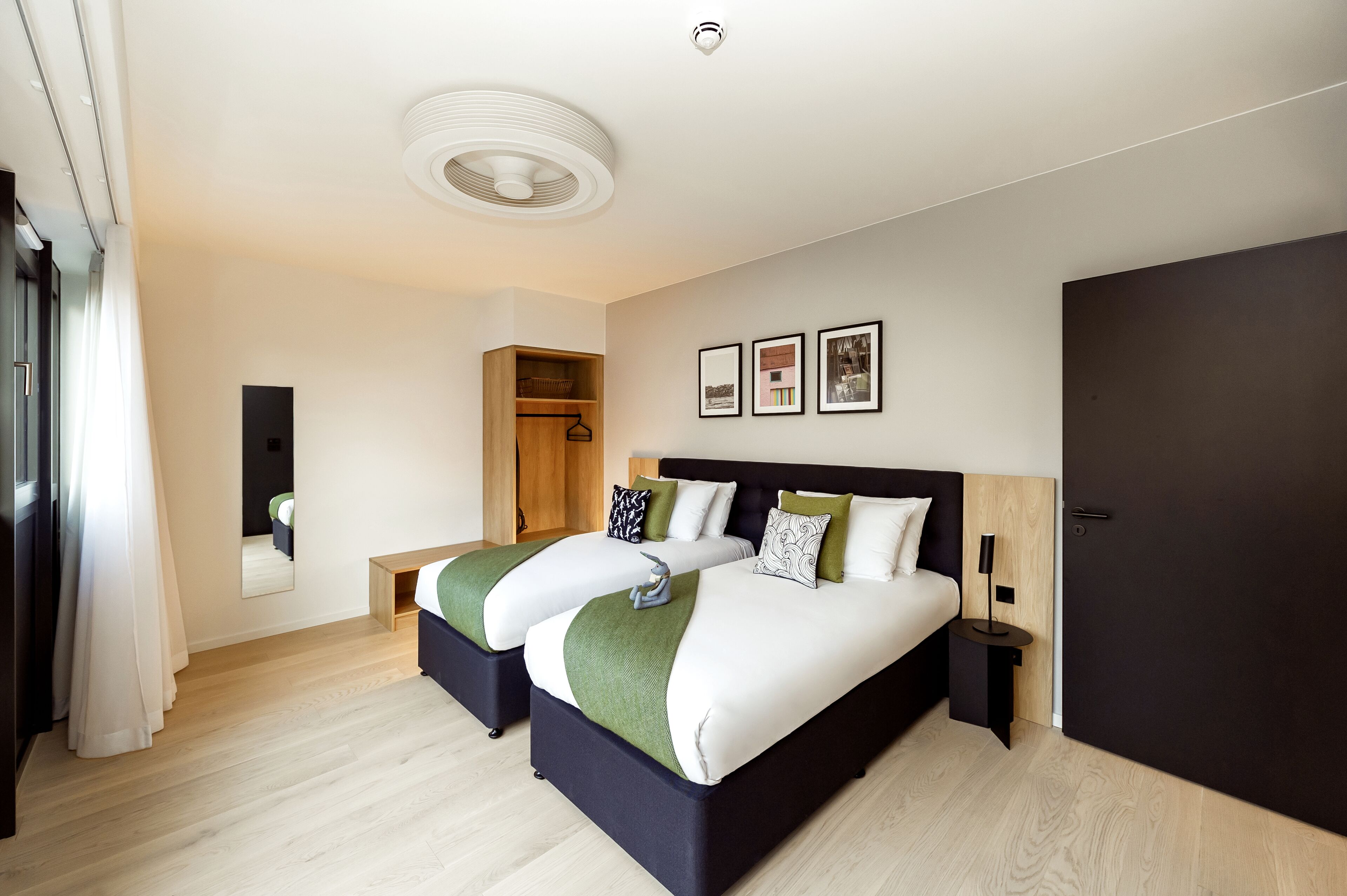 Une chambre d’hôtel moderne avec un grand lit, une table de chevet, une armoire et un miroir.