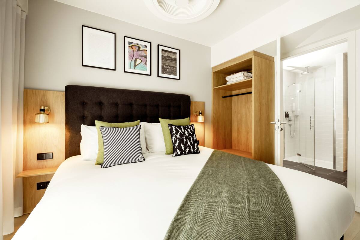 A neatly arranged bedroom with a large bed, bedside tables, and a wardrobe.