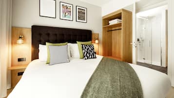 A neatly arranged bedroom with a large bed, bedside tables, and a wardrobe.
