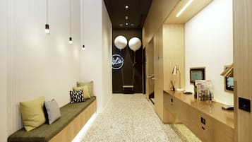 Un pasillo con un banco, una mesa de recepción y un letrero de neón.