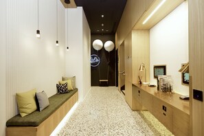 A hallway with a bench, a reception desk, and a neon sign. - Wilde Aparthotels, Berlin, Checkpoint Charlie (Berlin)