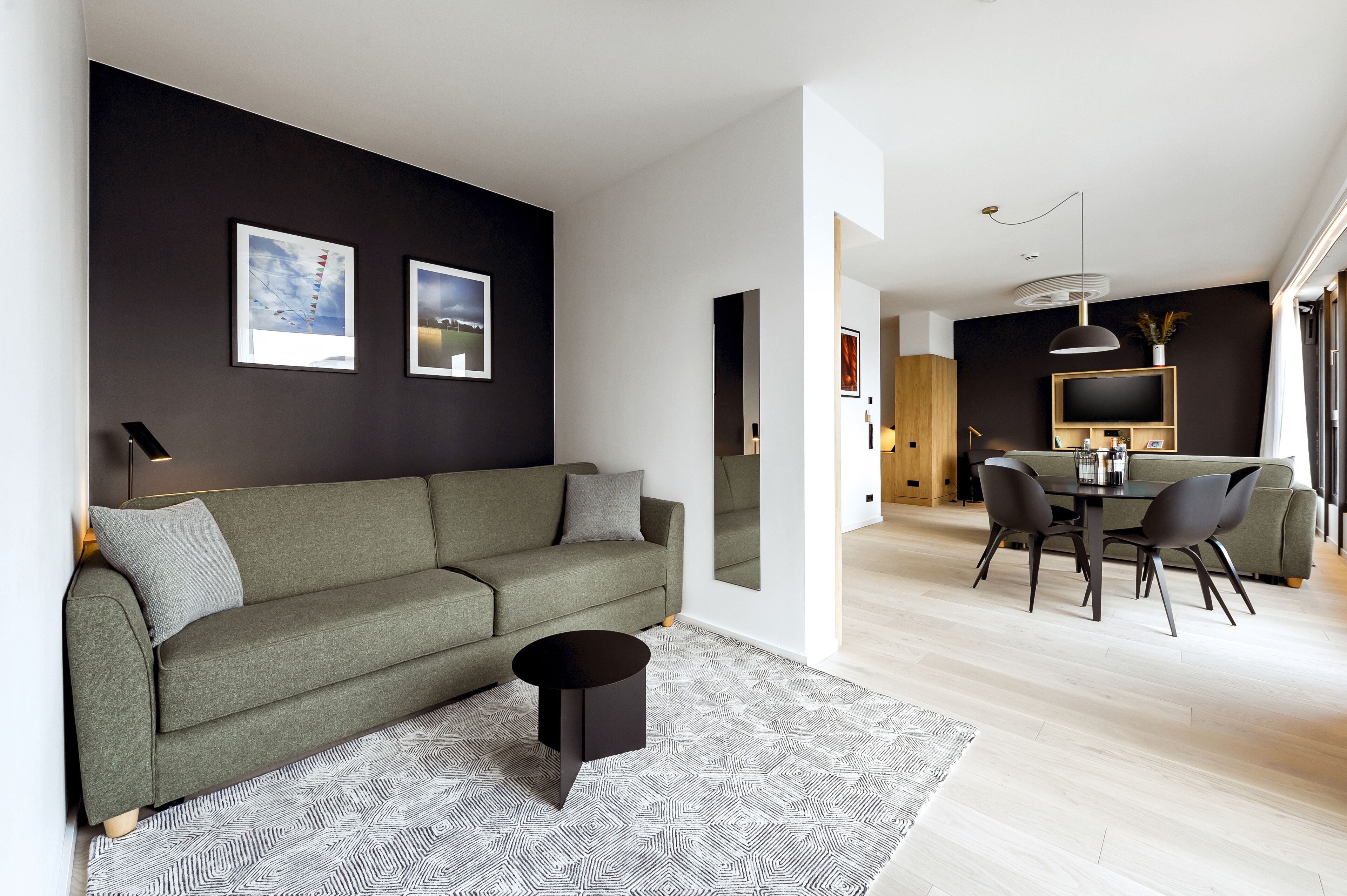Una sala de estar moderna con un sofá, una mesa de centro y un área de comedor con un televisor y sillas.