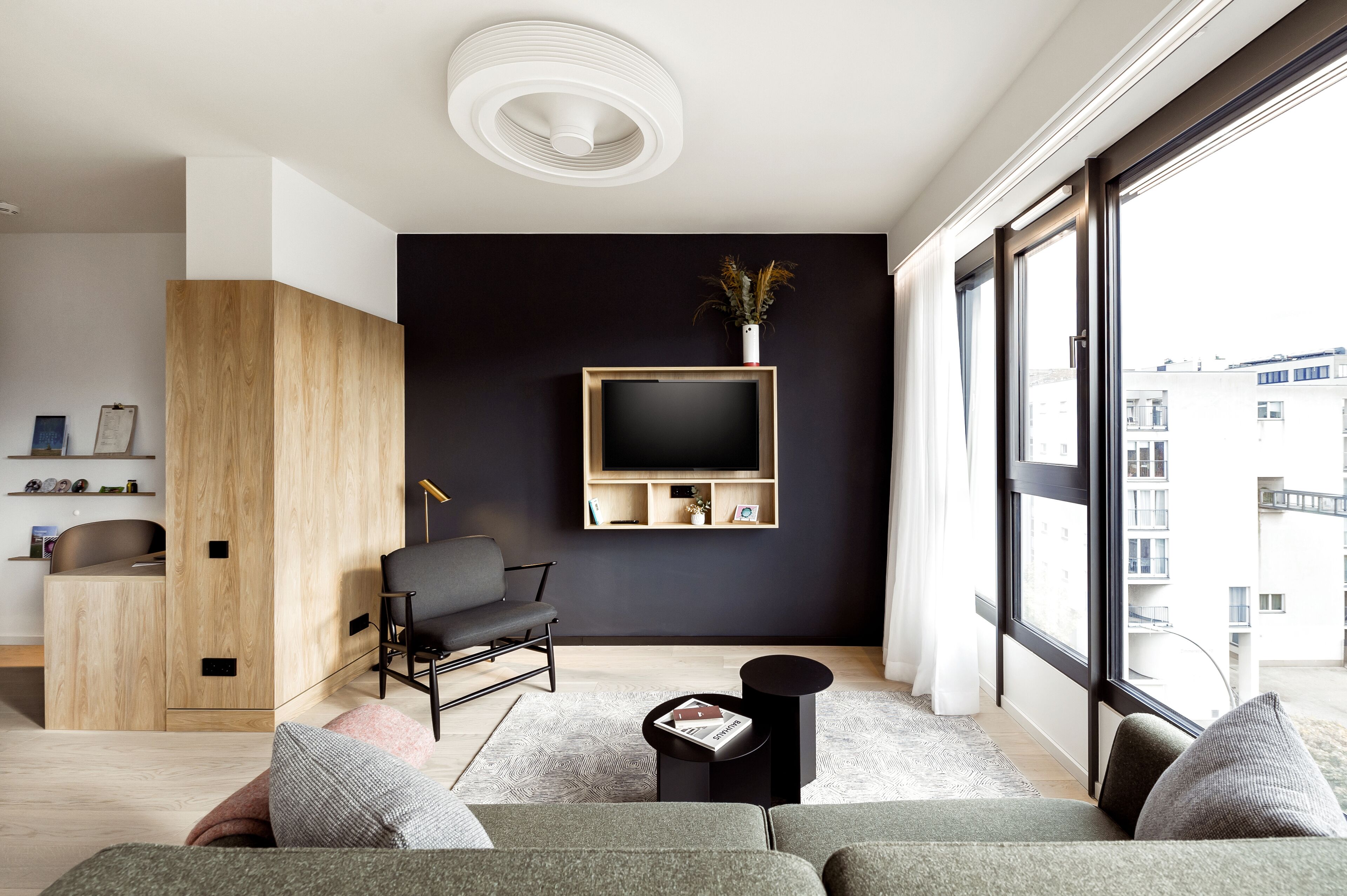 A modern living room with a sofa, a coffee table, and a TV mounted on the wall.