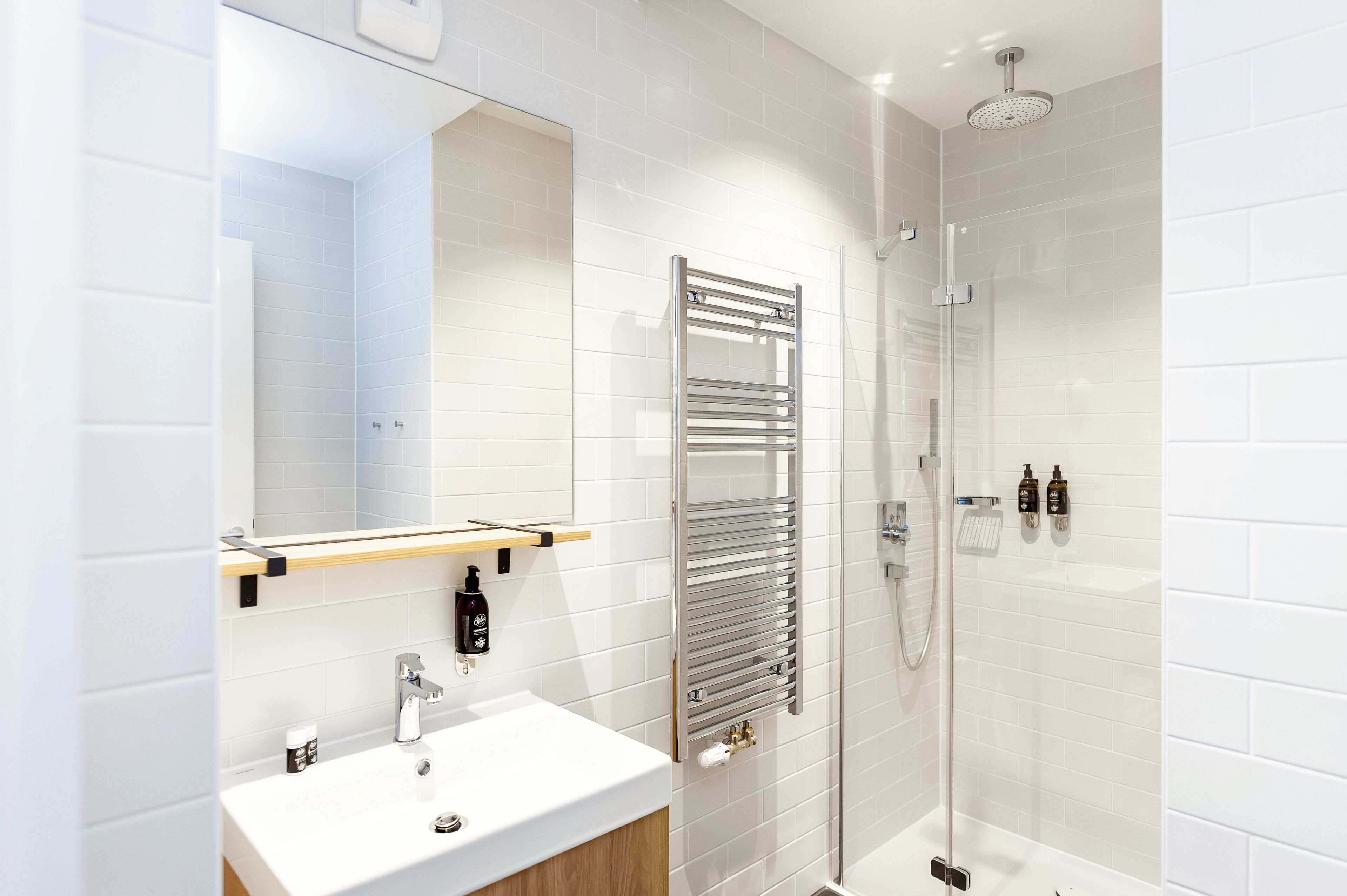 Une salle de bain moderne avec un lavabo blanc, un miroir et une douche.