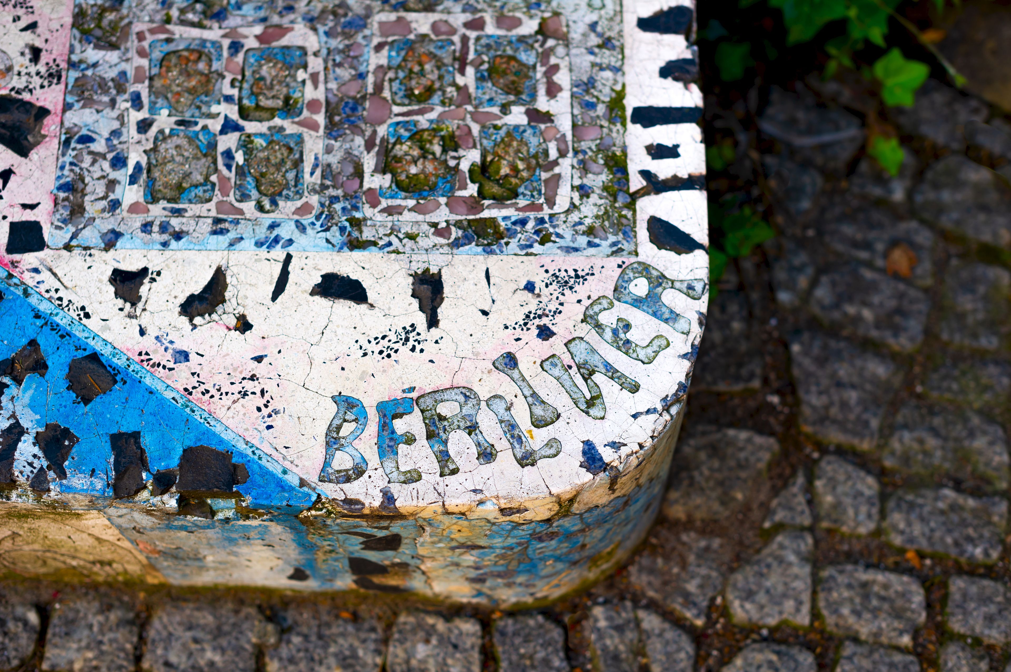 Eine abgenutzte, mosaikverlegte Fläche, auf der das Wort "BERLIN" teilweise zu erkennen ist.