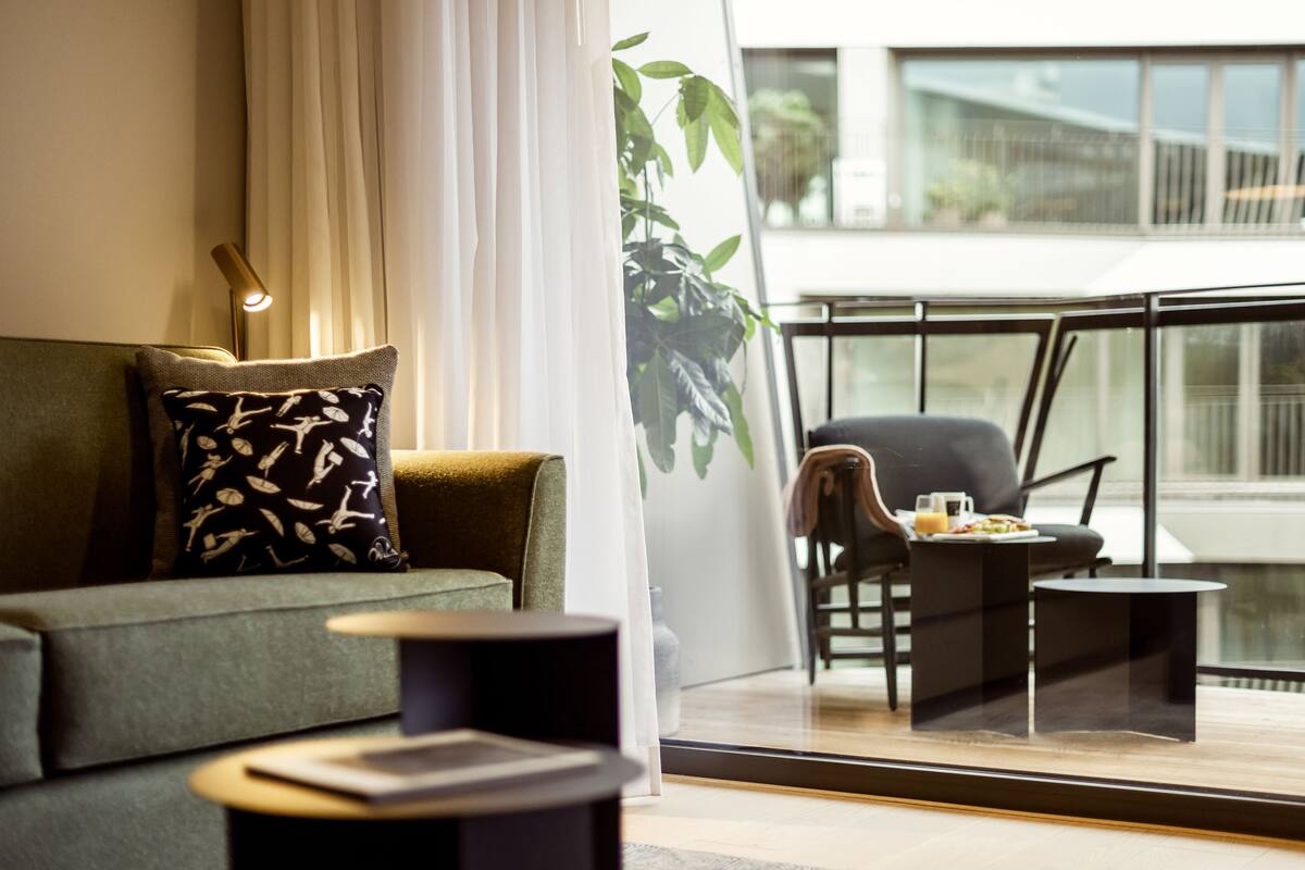 A modern living room with a sofa, a side table, and a chair by a large window.