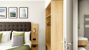 A modern hotel room with a tufted headboard, a wooden wardrobe, a bed with white and green bedding, and a bathroom with a white sink and towel rack.