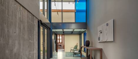 A modern interior with a concrete wall, a wooden bench, and a view into another room.
