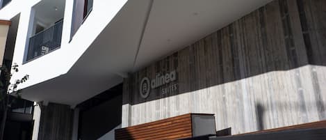 A modern building with a white facade, multiple balconies, and a sign for 'dinea Suites'.