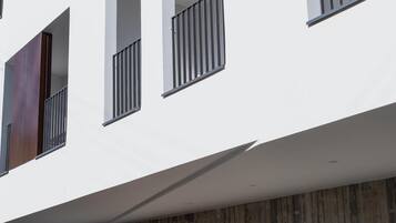 Un bâtiment moderne à la façade blanche, doté de nombreux balcons et d’une enseigne indiquant « Alinea Suites ».