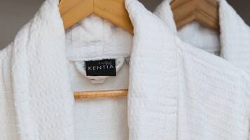 A white robe hanging on a wooden hanger with a tag labeled "Hotel Kentia".