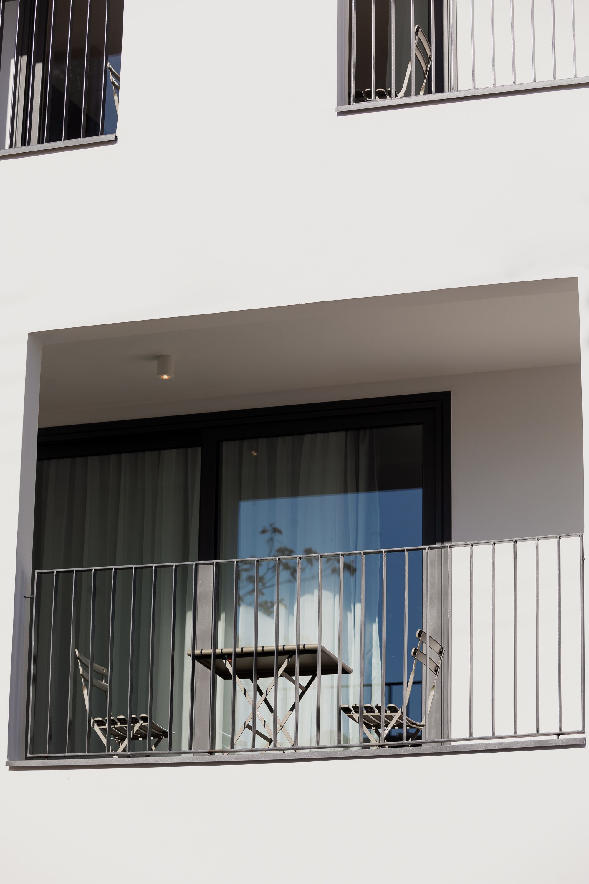 A balcony with metal railings and a table with chairs.