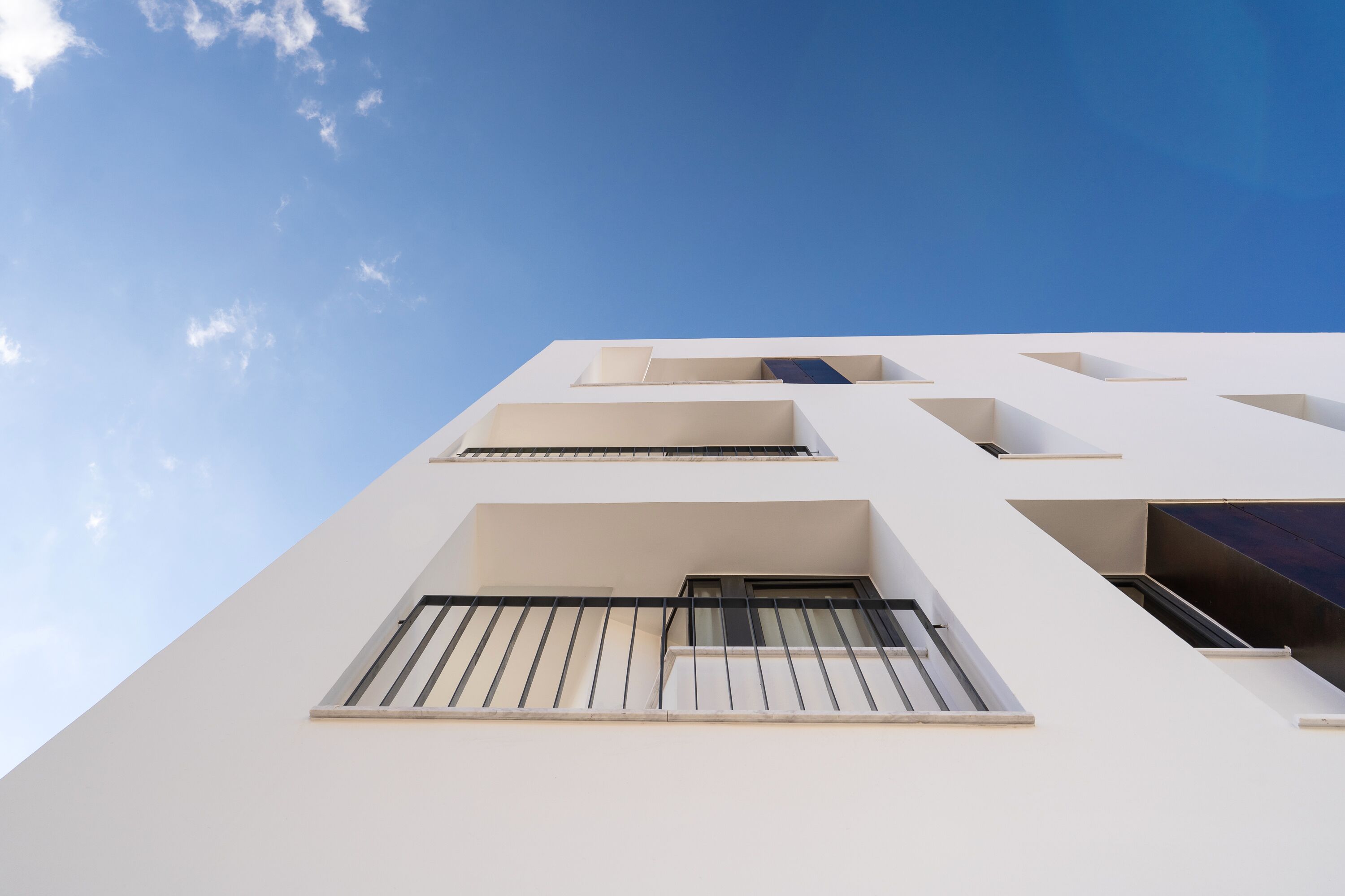 A modern building with a white facade and multiple balconies.
