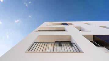 A modern building with a white facade and multiple balconies.