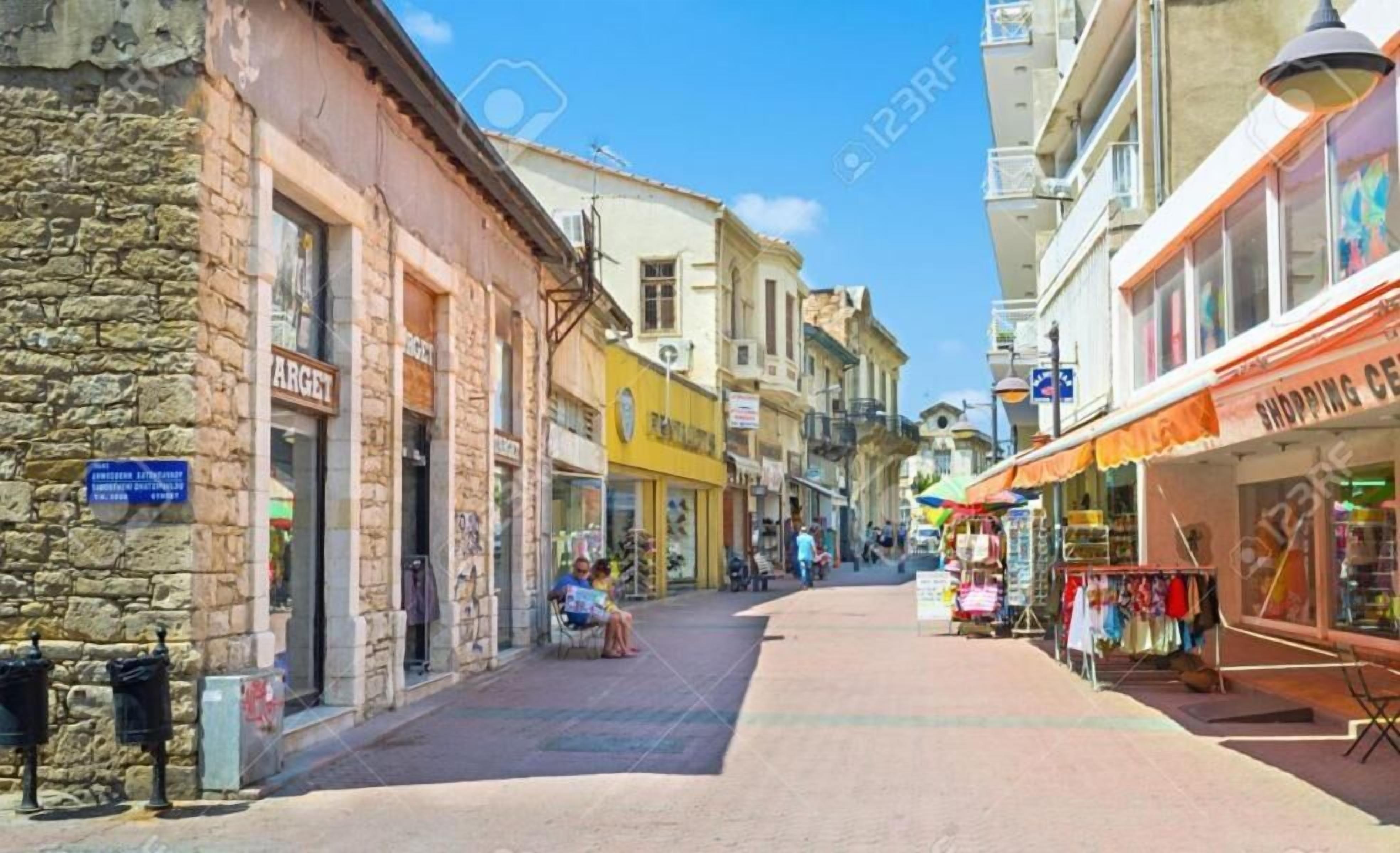 A narrow street lined with shops and a stone building on the left.