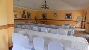 A conference room with long tables, white chairs, and a chandelier.