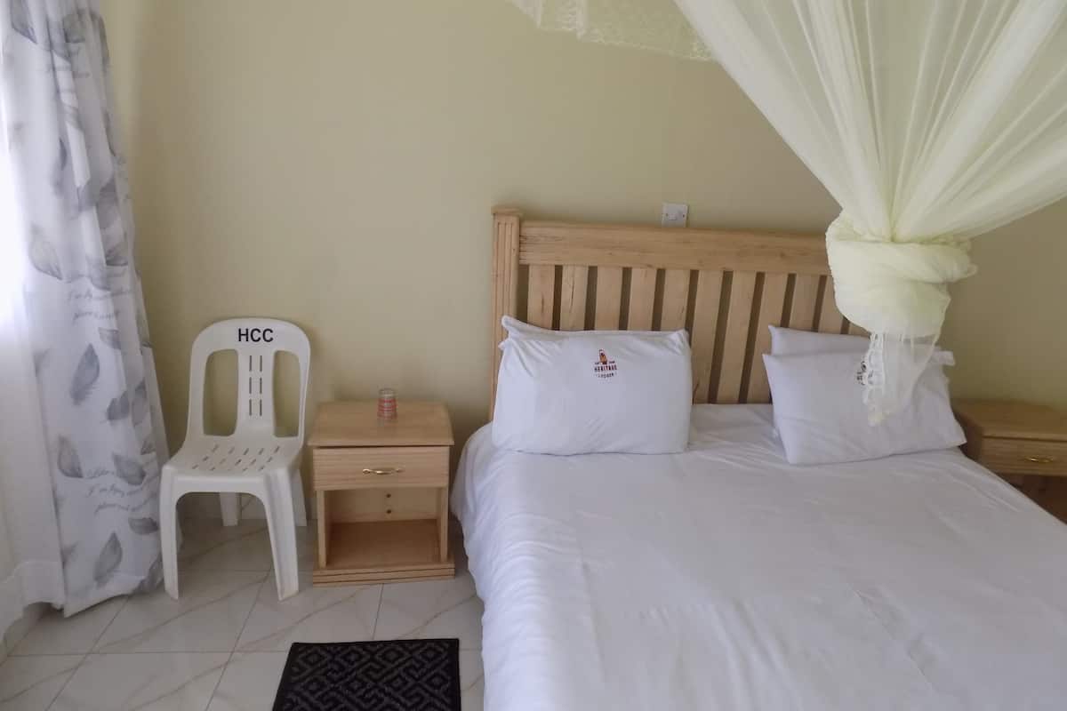 A bedroom with a bed, a nightstand, a chair, a bedside table, and a mosquito net.
