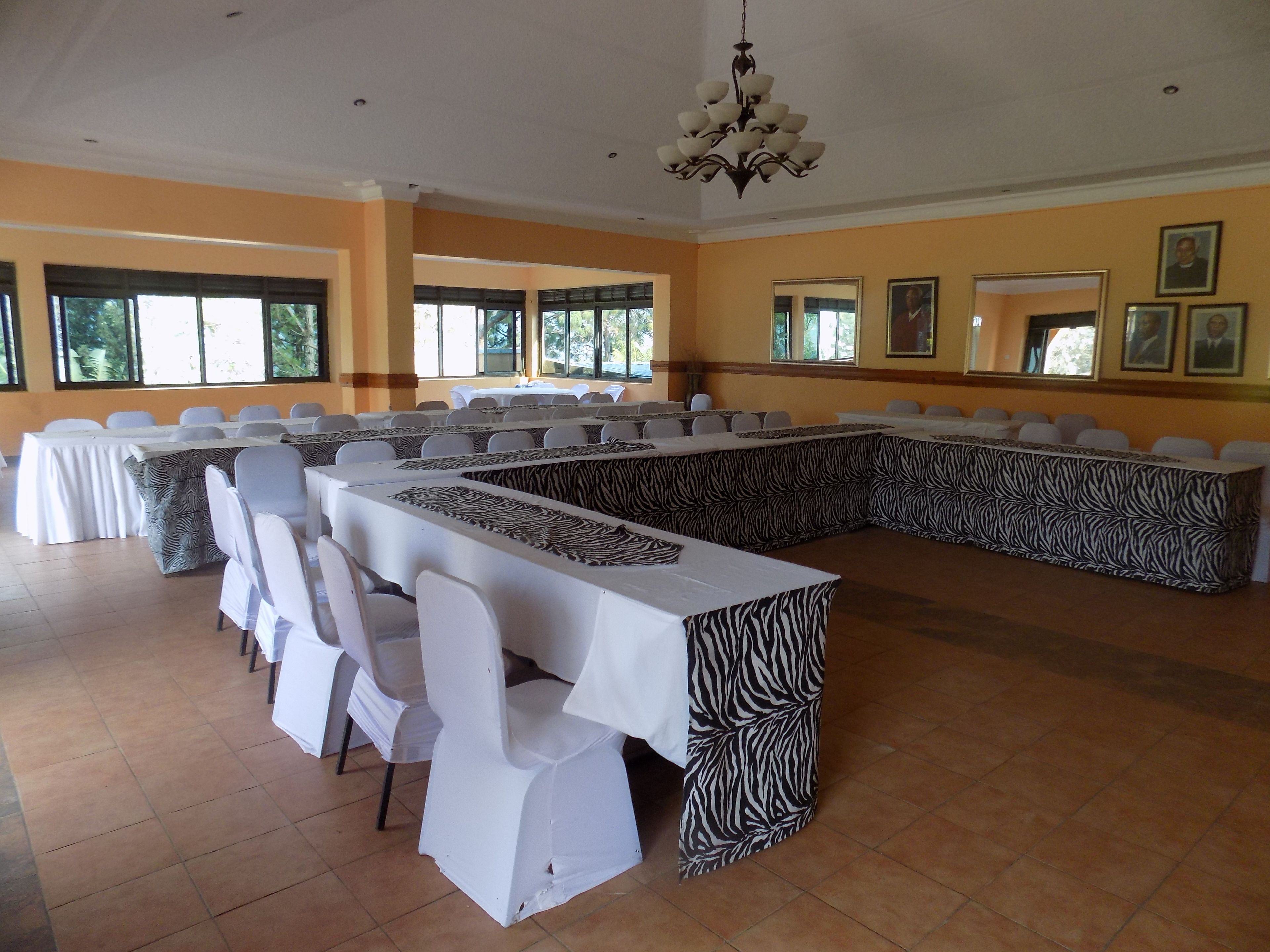A conference room with multiple tables and chairs, large windows, and a chandelier.
