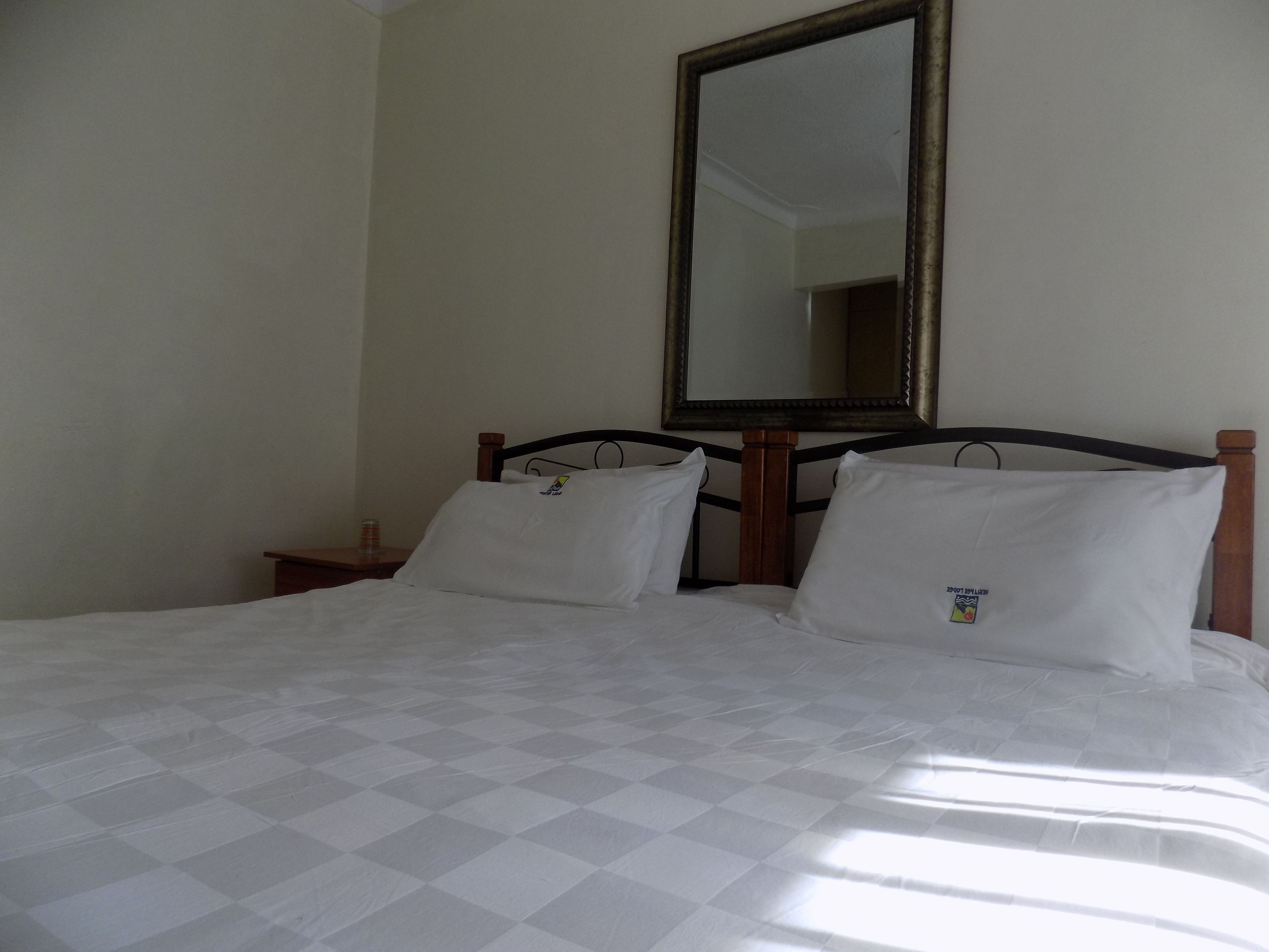 Een hotelkamer met een bed, een nachtkastje en een grote spiegel aan de muur.