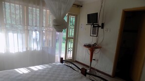 Una camera da letto con un letto, un comodino, una televisione a parete e una finestra con tende.