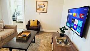 A living room with a sofa, a coffee table, a TV, and a framed picture on the wall. - The Cozy Murray Bungalow fast WIFI free parking!  (Murray)