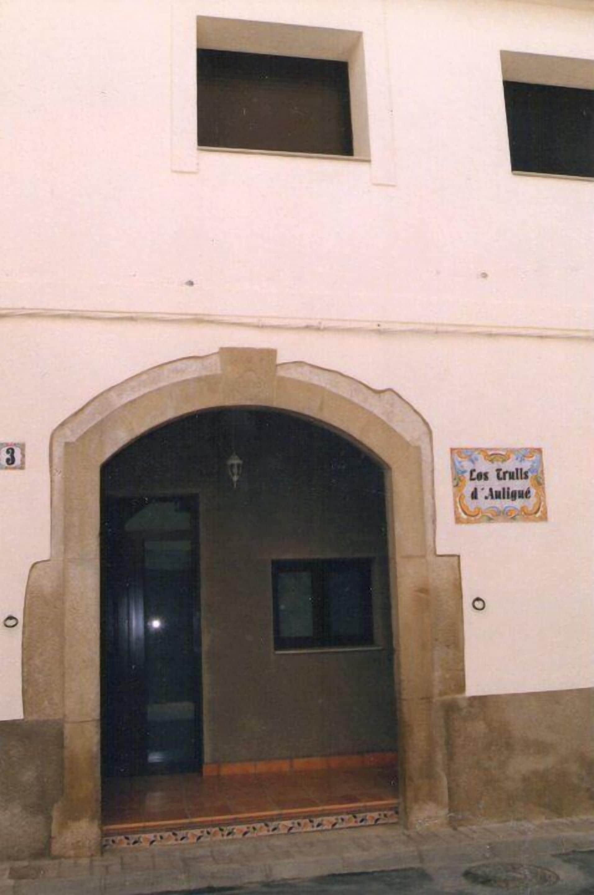 A building with a large arched entrance, a small window above the door, and a sign on the wall.