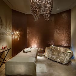 Experience relaxation in this serene spa room, featuring a massage table and stone bath area.