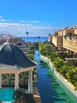 A resort with a central water feature, a pool, and a view of the ocean.