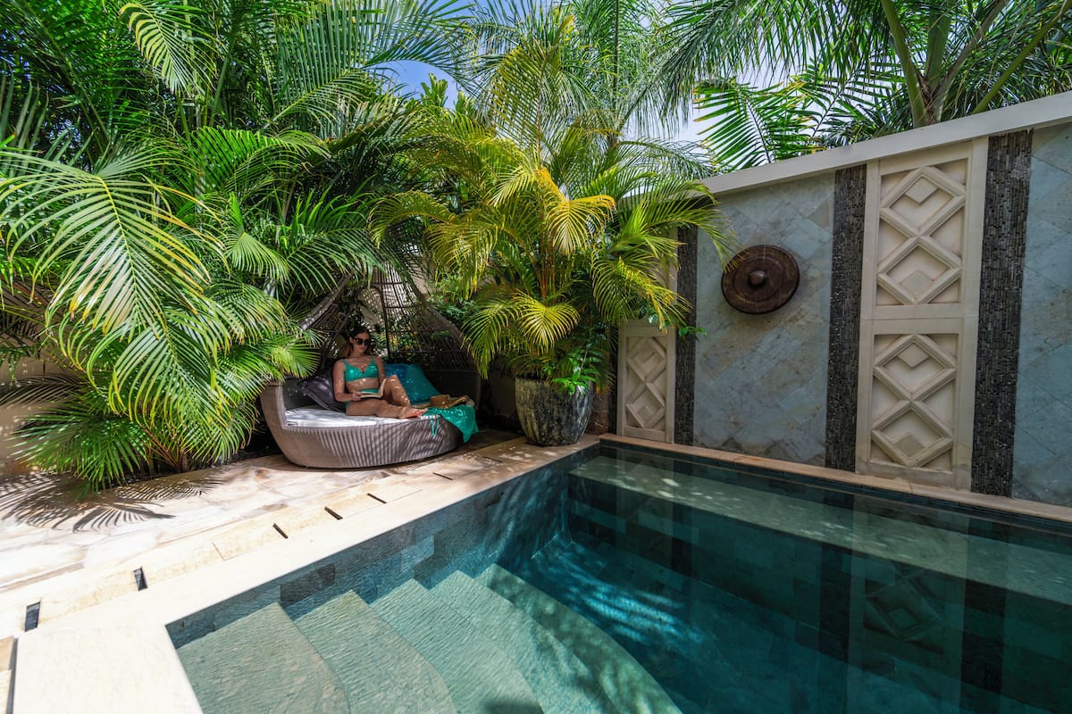A poolside area with a built-in seating area surrounded by lush greenery.
