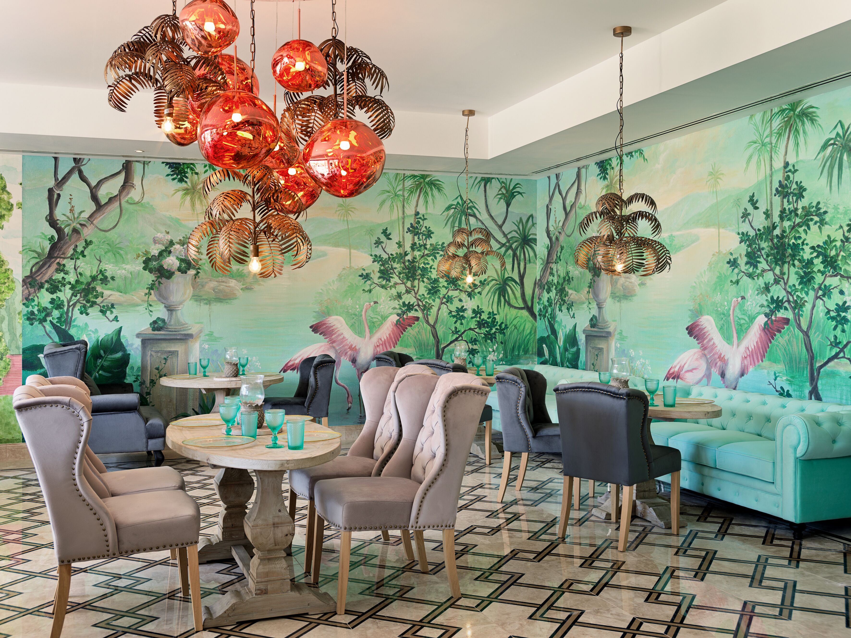 A dining area with a round table, chairs, and a mural of a tropical scene.