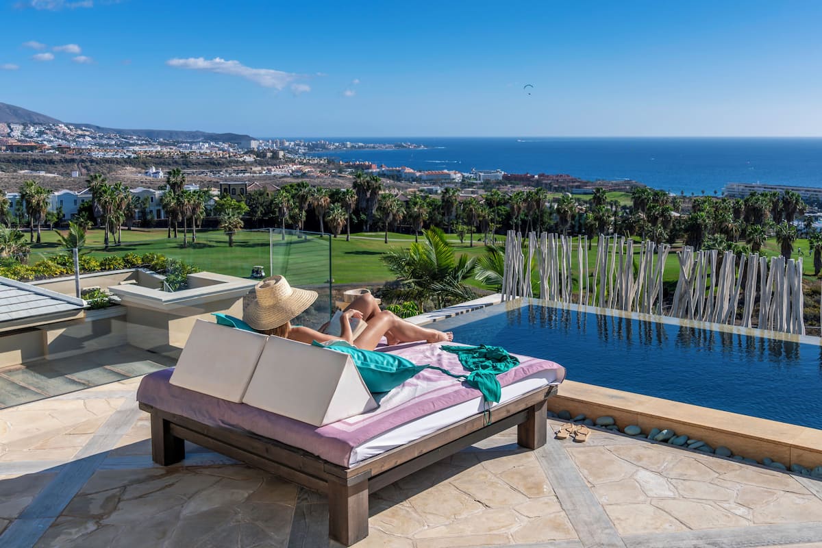 A poolside lounge with a view of the ocean and a golf course.