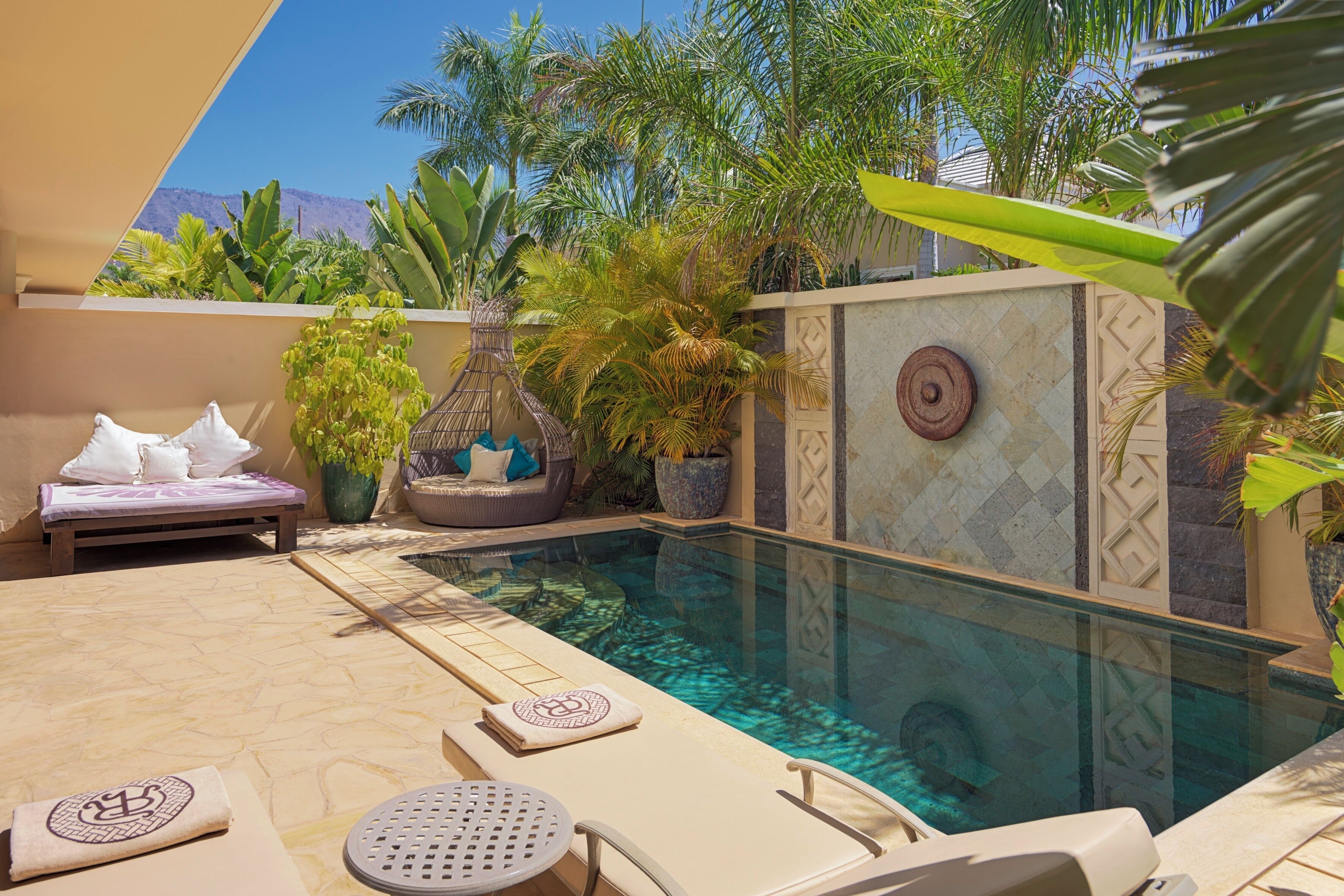 A poolside area with lounge chairs, a small table, and a decorative wall.