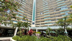 A high-rise hotel with multiple balconies, a central vertical feature, and a landscaped garden area. - Ilikai Apt 302 -Newly Renovated October 2025- Studio with  Ocean & Harbor Views Modern Updates (Waikiki)